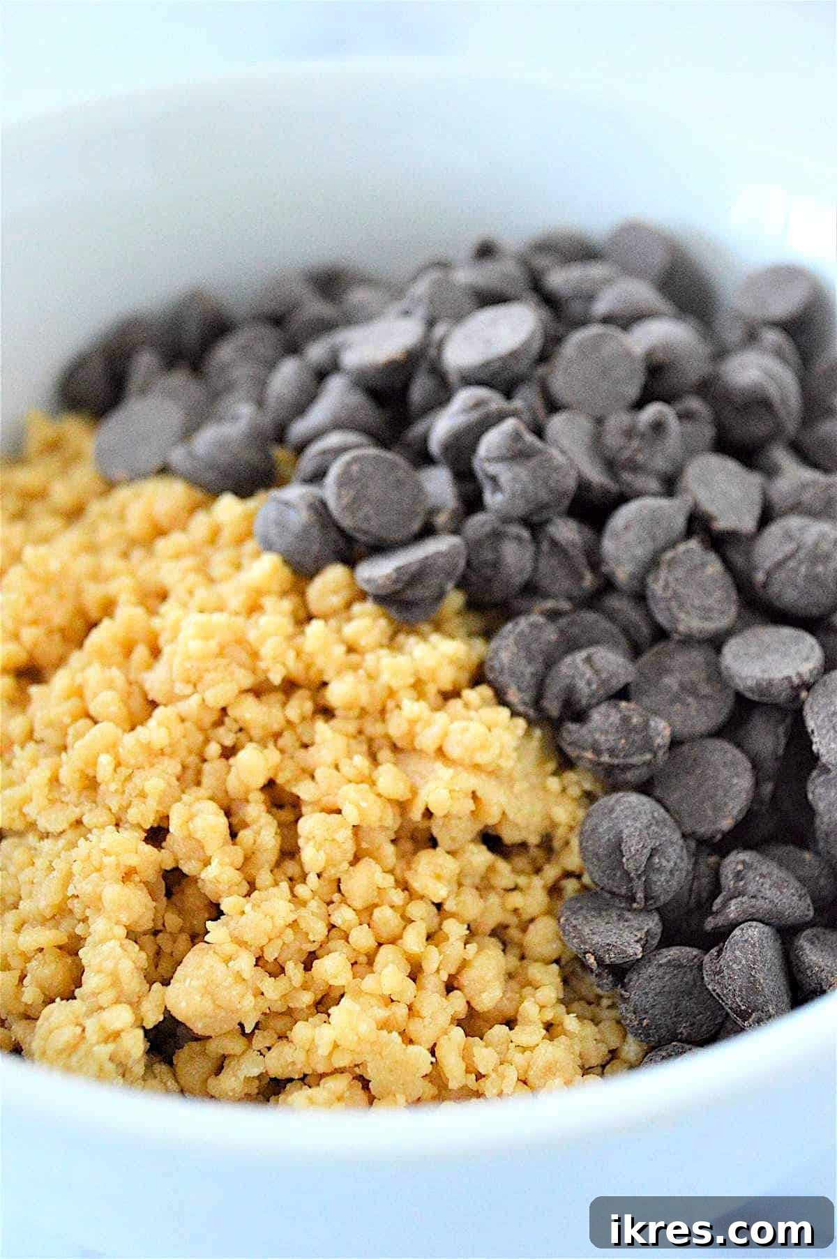 Easy No-Bake Power Bites 7 A process image demonstrating how to manually mix chocolate chips into the no-bake energy ball dough within a bowl, ensuring even distribution.