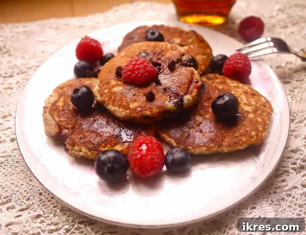 Gluten-Free Paleo Berry Chocolate Chip Pancakes 2 Close-up of golden brown Raspberry, Blueberry, and Chocolate Chip Paleo Pancakes stacked on a plate.