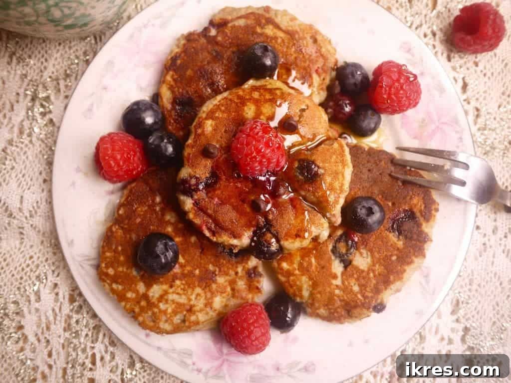 Gluten-Free Paleo Berry Chocolate Chip Pancakes 3 Stack of freshly made Paleo pancakes, showing the inside with visible raspberries, blueberries, and chocolate chips.