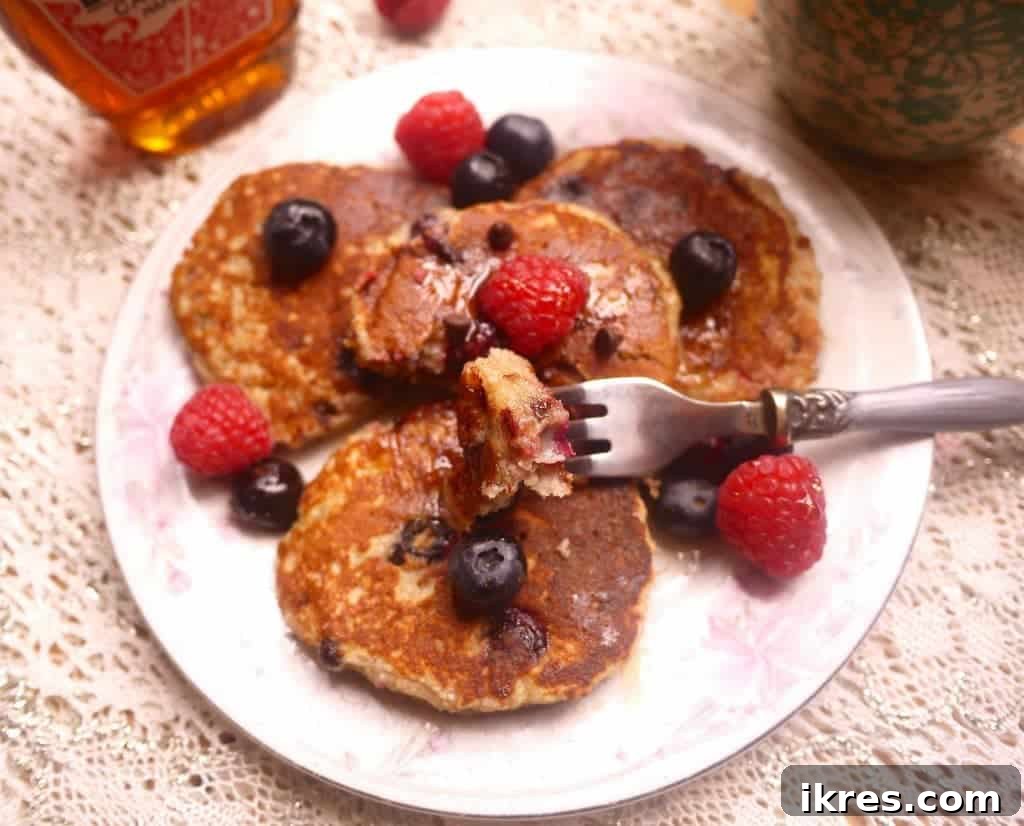 Gluten-Free Paleo Berry Chocolate Chip Pancakes 4 Paleo pancakes drizzled with maple syrup, garnished with fresh berries and a dusting of powdered sugar.