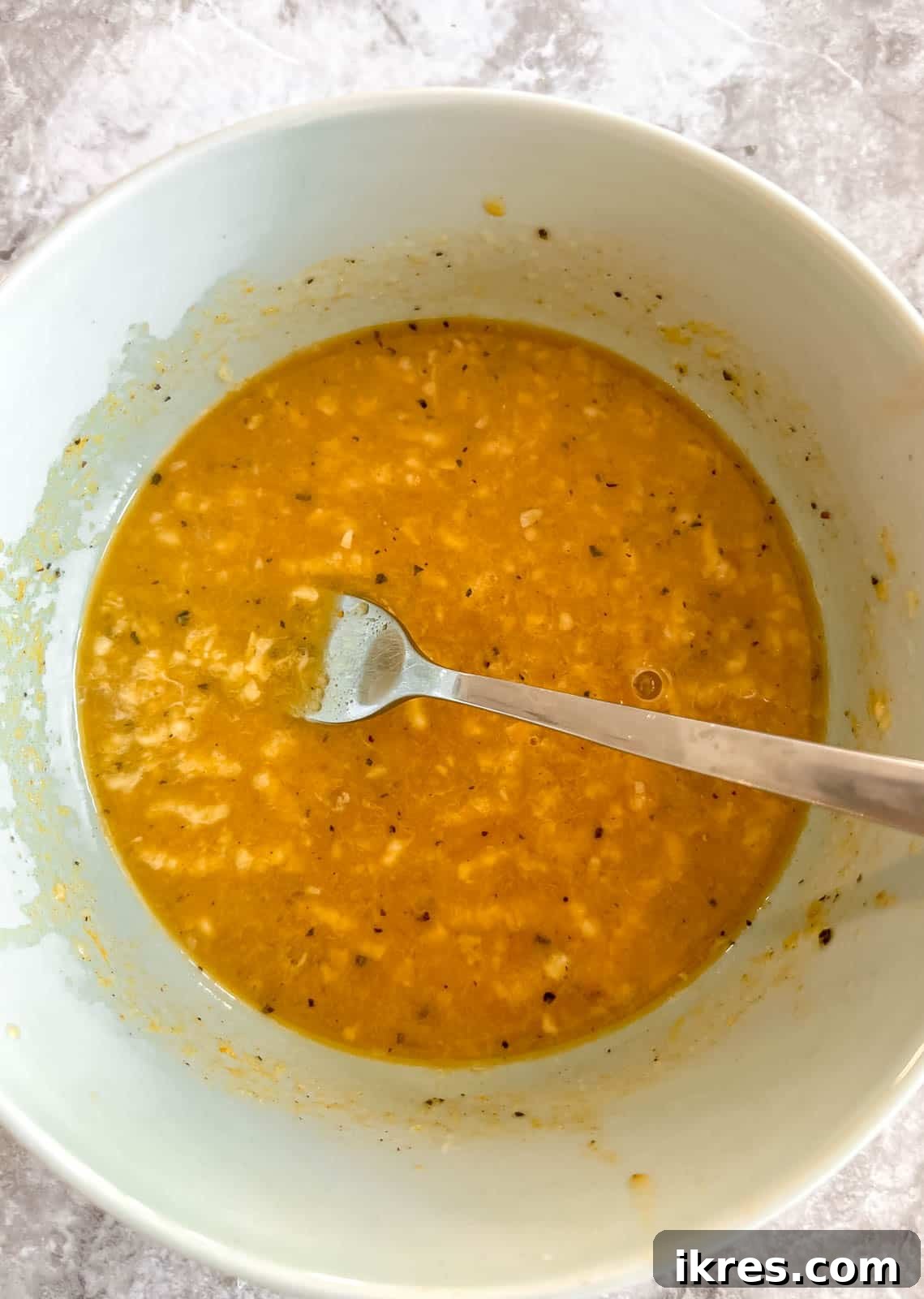 Bowl with lemon juice, turmeric, honey, ginger, garlic, salt, and pepper for salmon sauce.