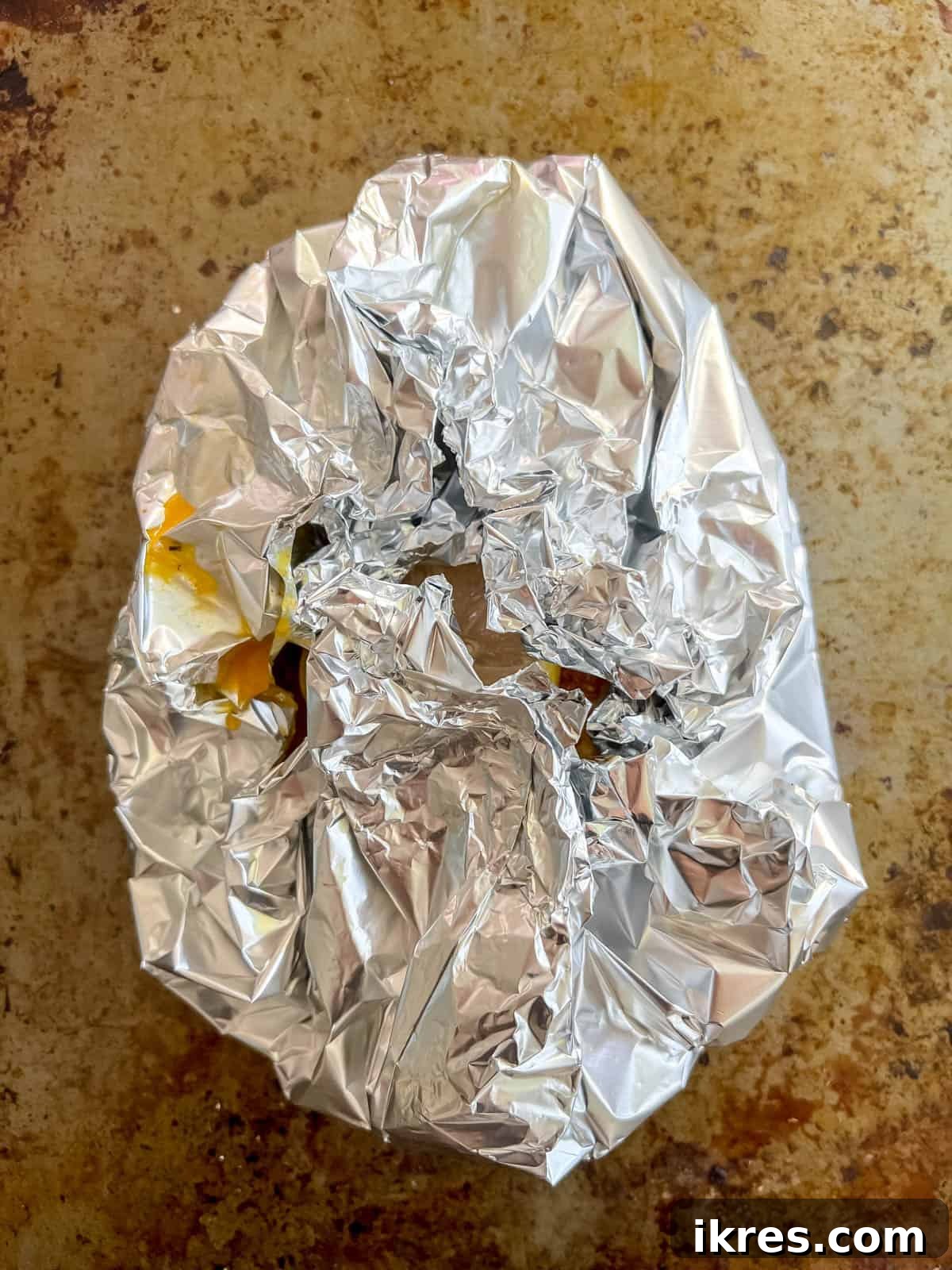 Salmon wrapped securely in aluminum foil, ready for baking.