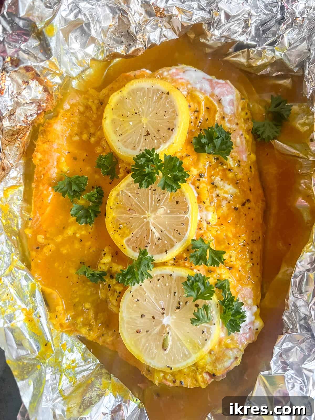 Freshly baked turmeric salmon in foil, still in the packet on a baking sheet.