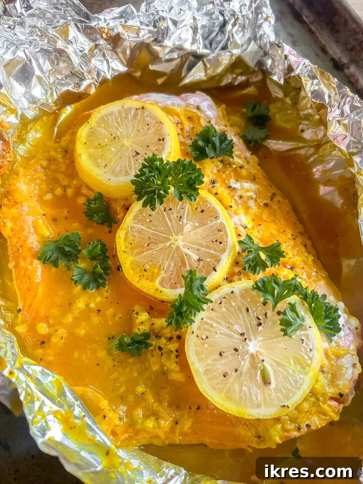 Side angle view of freshly baked lemon ginger turmeric salmon, showing its tender, flaky texture.