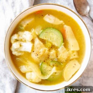 A bowl of hot chicken and leek soup with visible vegetables and chicken pieces.