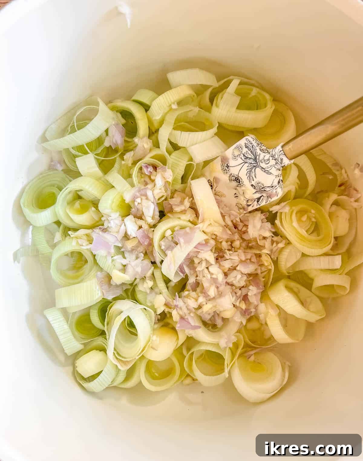 Minced leeks, garlic, and shallots sautéing in olive oil in a large soup pot.