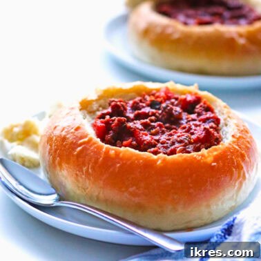 Effortless Homemade Chili 4 A close-up of Quick and Easy Chili served in a rustic bread bowl, garnished with melted mozzarella cheese.