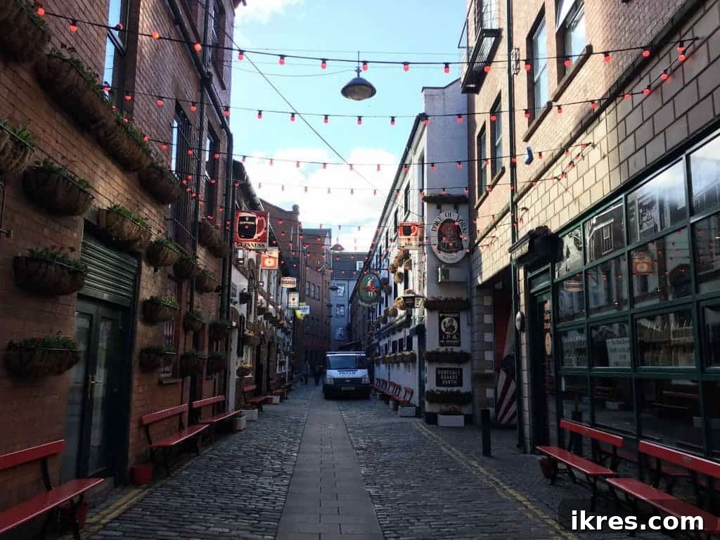 The lively street leading to Duke of York in Belfast's Cathedral Quarter, adorned with lights and street art.