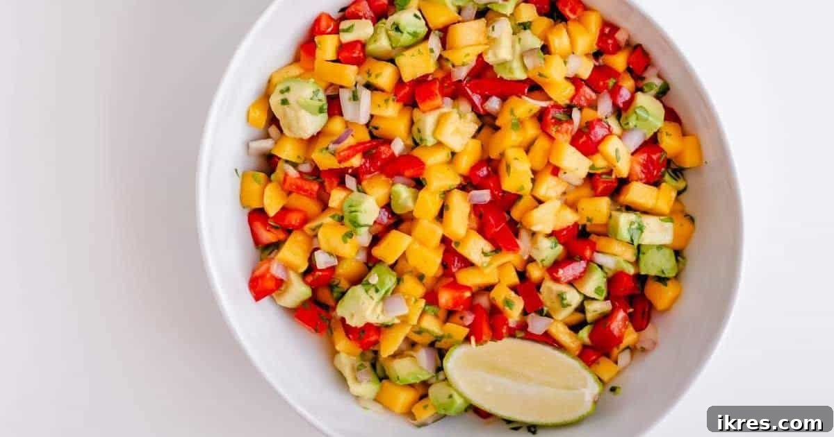 Tropical Mango Avocado Salsa 5 A glistening bowl of homemade mango and avocado salsa garnished with a fresh lime wedge, ready to be devoured.