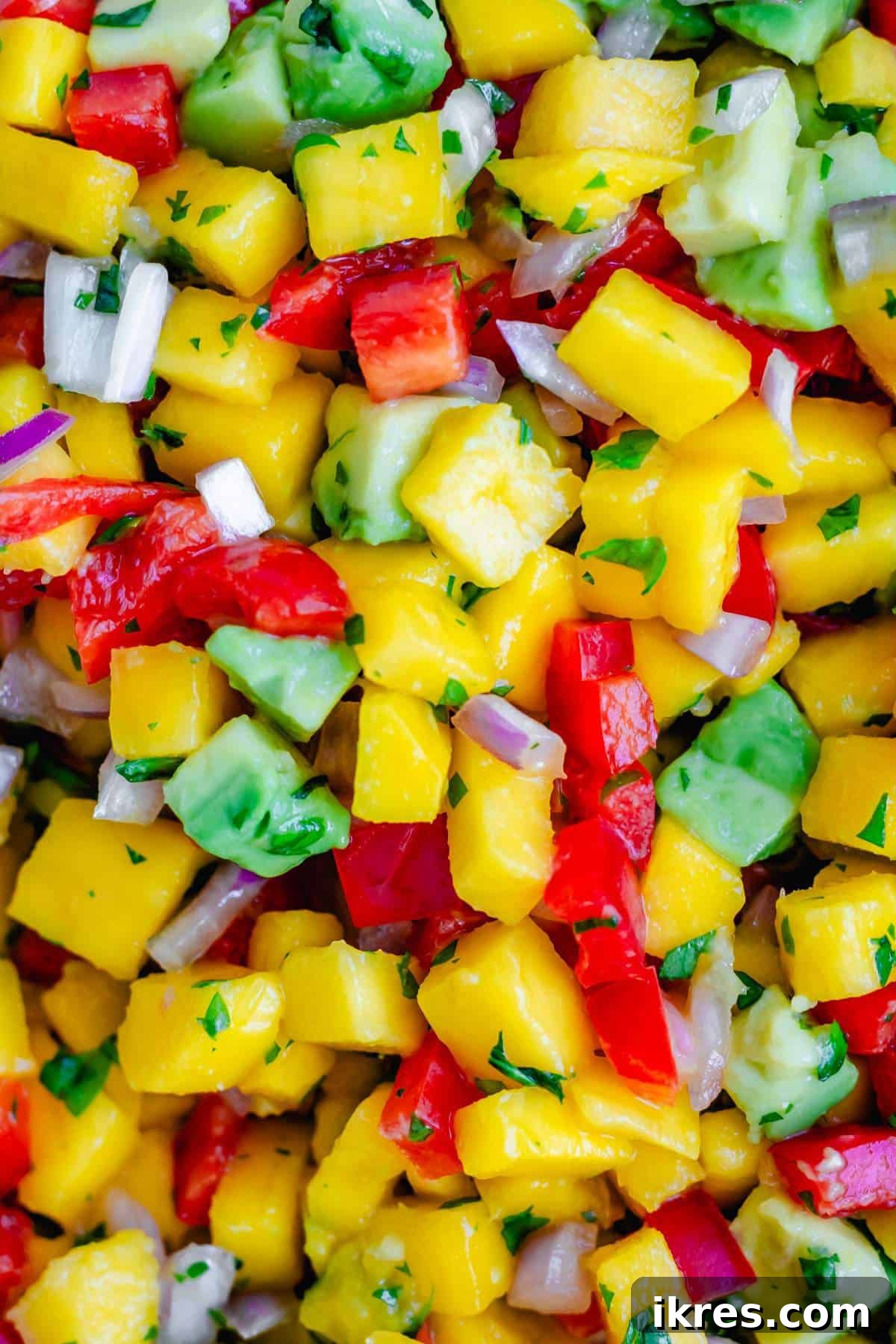 Tropical Mango Avocado Salsa 6 A close-up view of freshly diced mangoes, avocados, bell peppers, and red onions, showcasing their perfect texture and vibrant colors for salsa.