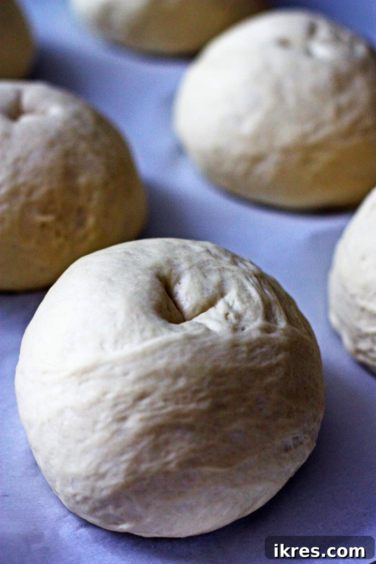 Raw bread bowl dough balls with an 'X' cut on top, ready for baking.