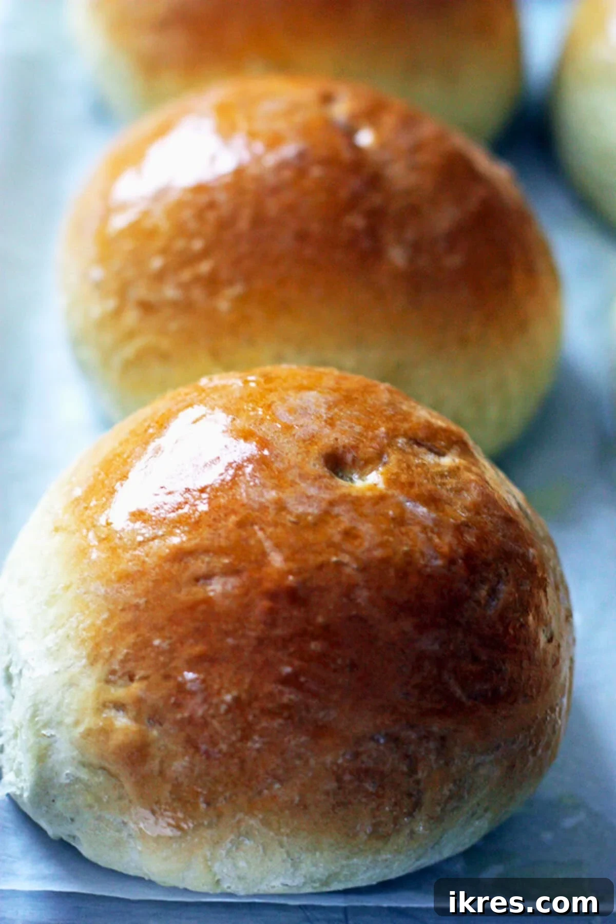 Freshly baked and buttered bread bowls cooling on parchment paper.