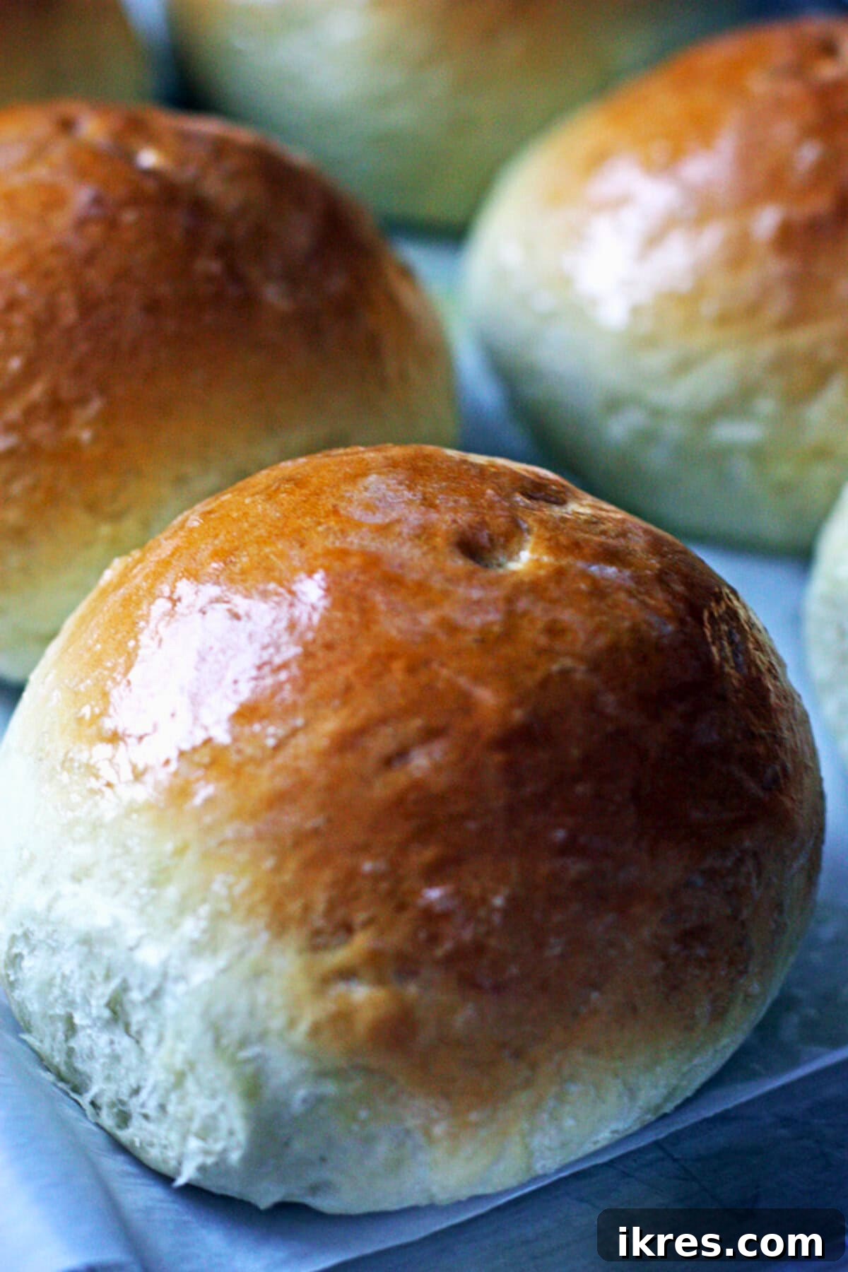 Freshly baked bread bowls cooling on a wire rack with parchment paper.