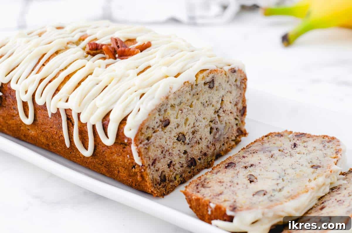 Buttermilk Banana Bread Perfection 2 A beautifully sliced loaf of buttermilk banana bread adorned with chopped nuts and a delicate drizzle of cream cheese frosting.