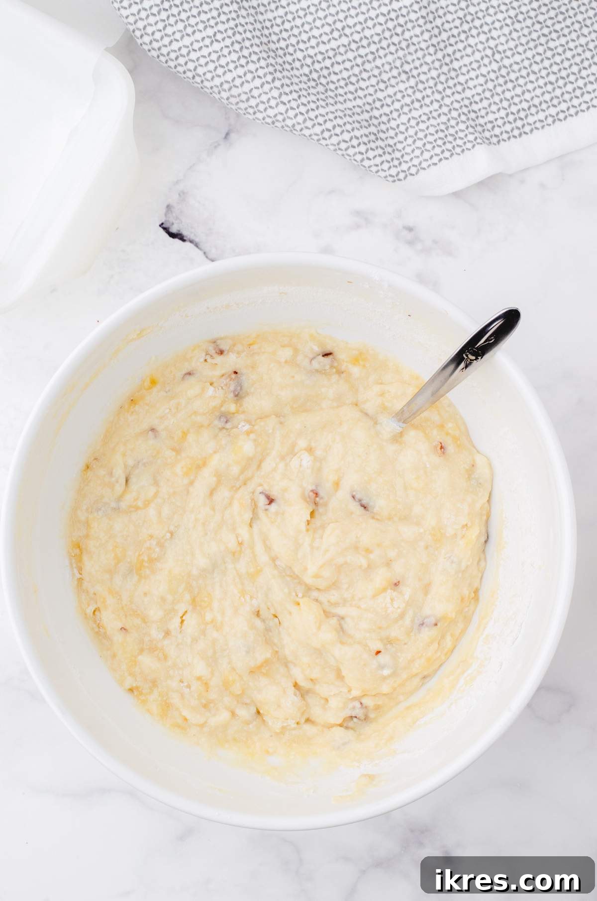 Buttermilk Banana Bread Perfection 7 A rich, golden brown buttermilk banana bread batter, perfectly mixed and ready for baking, sits in a white mixing bowl.