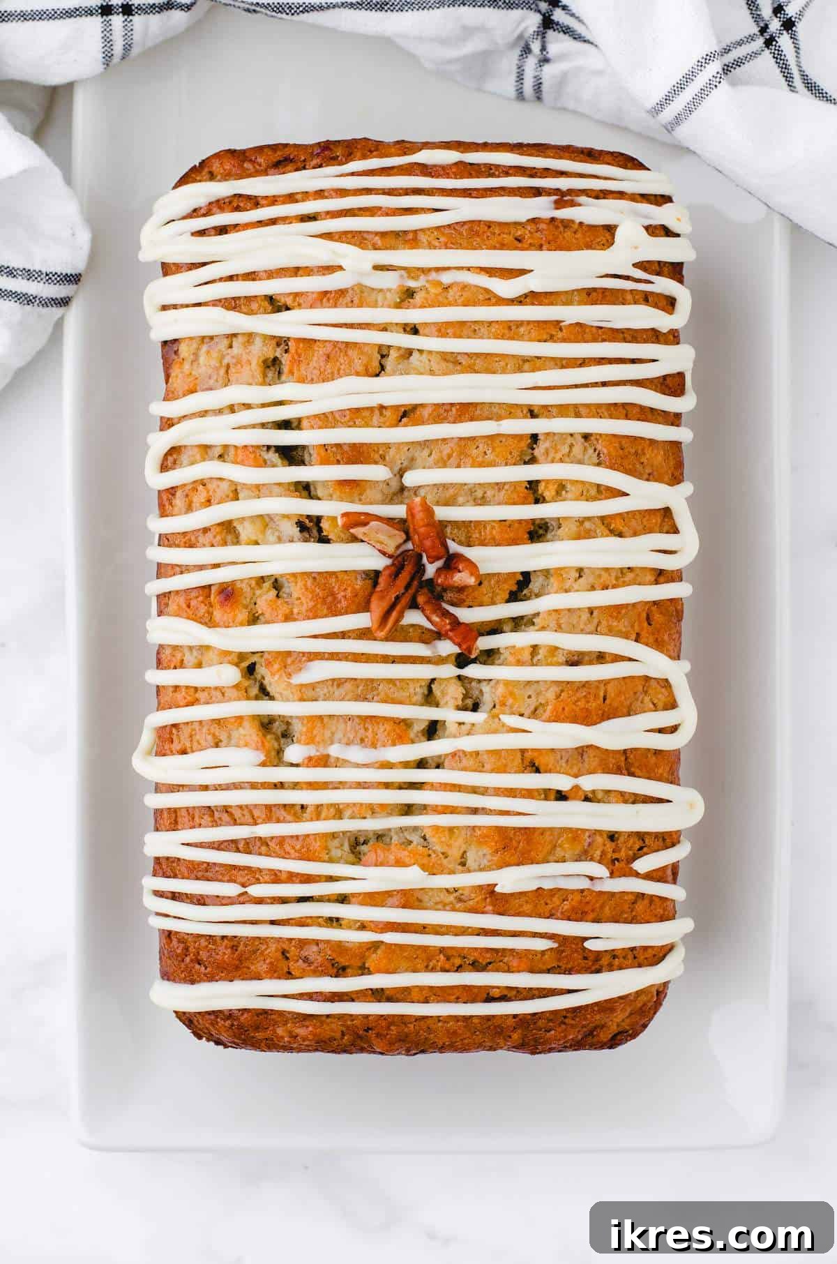 Buttermilk Banana Bread Perfection 9 A freshly baked loaf of buttermilk banana bread, beautifully adorned with a generous drizzle of homemade Cream Cheese Frosting.