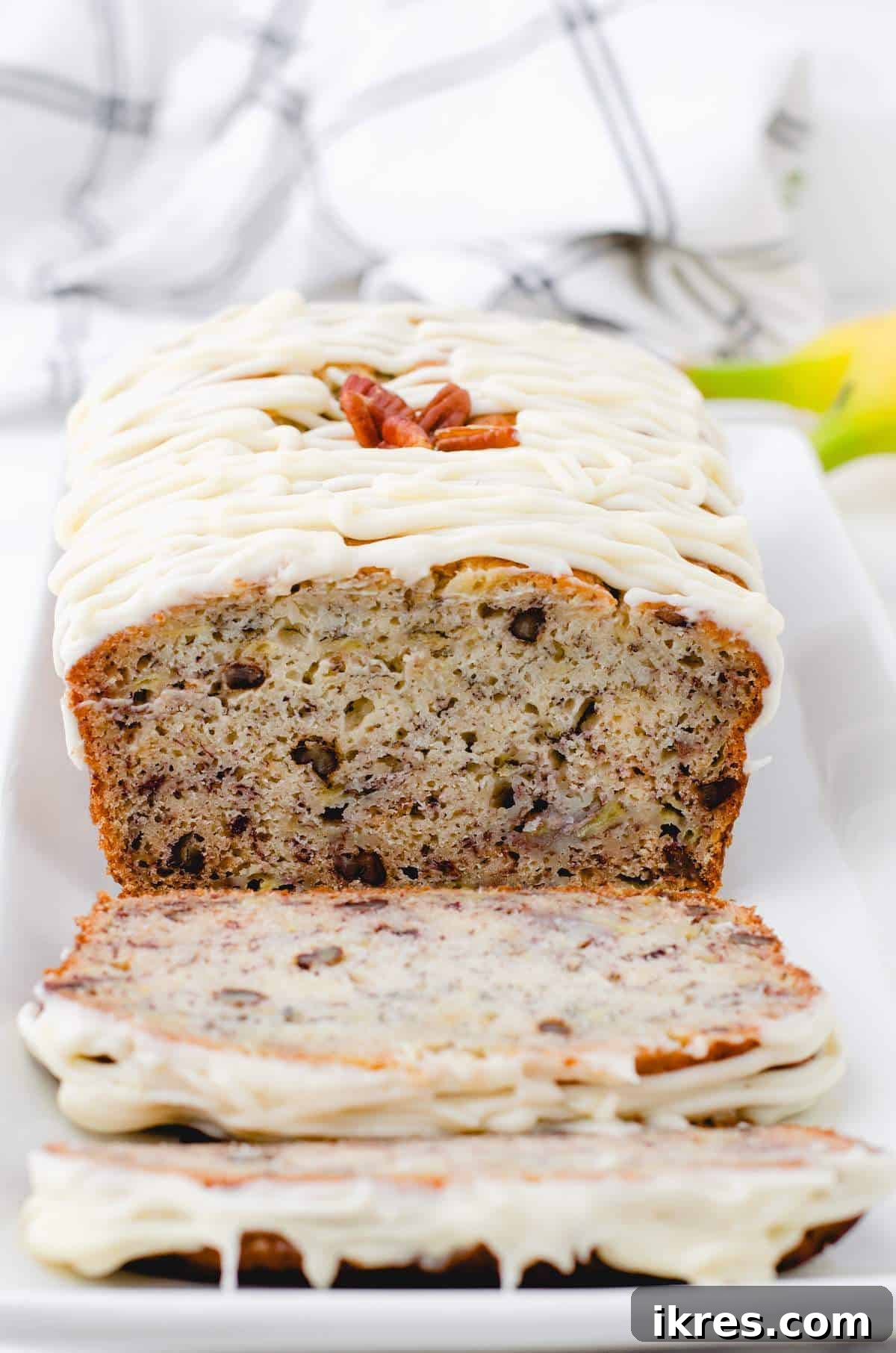 Buttermilk Banana Bread Perfection 10 A perfectly baked slice of buttermilk banana bread with cream cheese frosting, presented on a white plate, revealing its tender, moist interior.