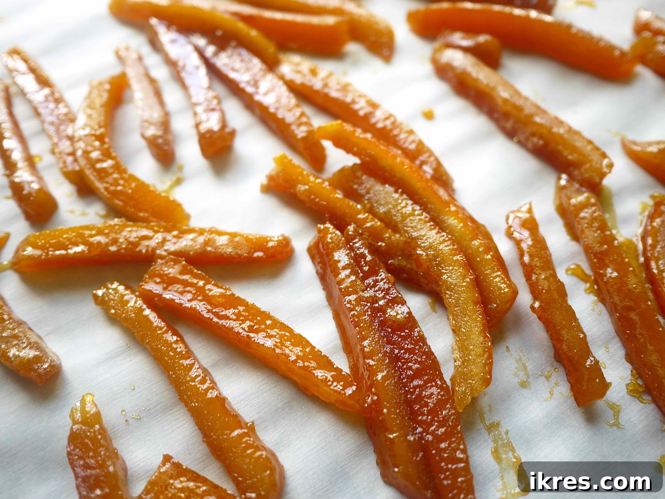 Paleo Honey Candied Orange Peels 9 Close-up of golden honey-candied orange peels arranged on parchment paper, glistening and ready.