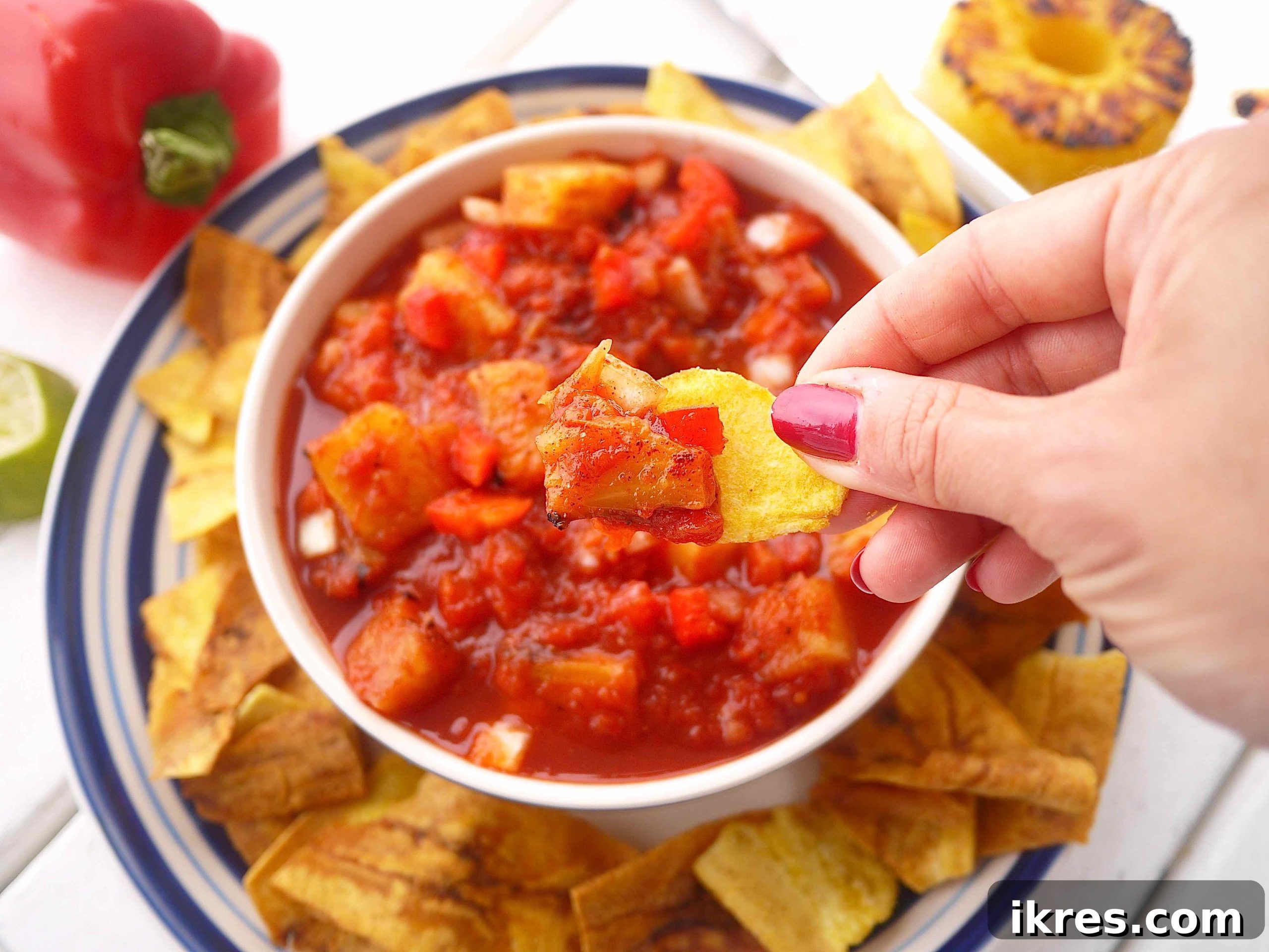 Sunshine & Smoke Salsa 3 A crispy tortilla chip perfectly dipped into a vibrant bowl of homemade sweet and spicy grilled pineapple salsa, highlighting its appetizing texture.
