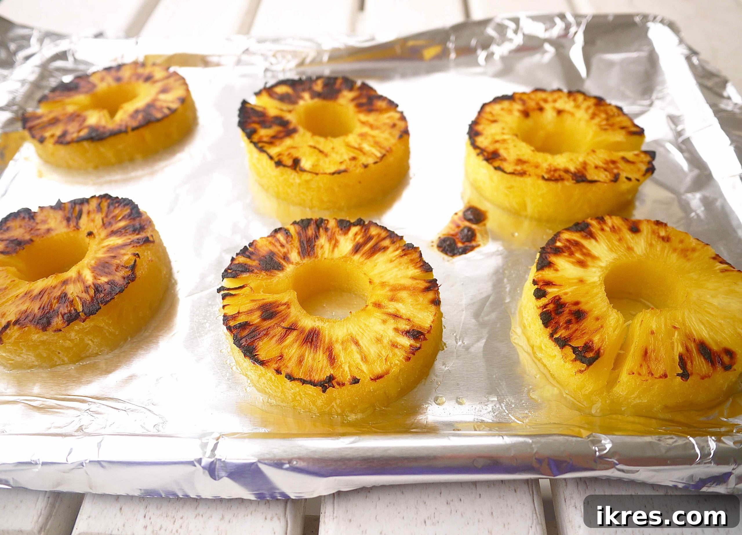 Sunshine & Smoke Salsa 4 Perfectly grilled pineapple rings, slightly caramelized and beautifully charred, fresh out of the oven on a baking sheet lined with foil.