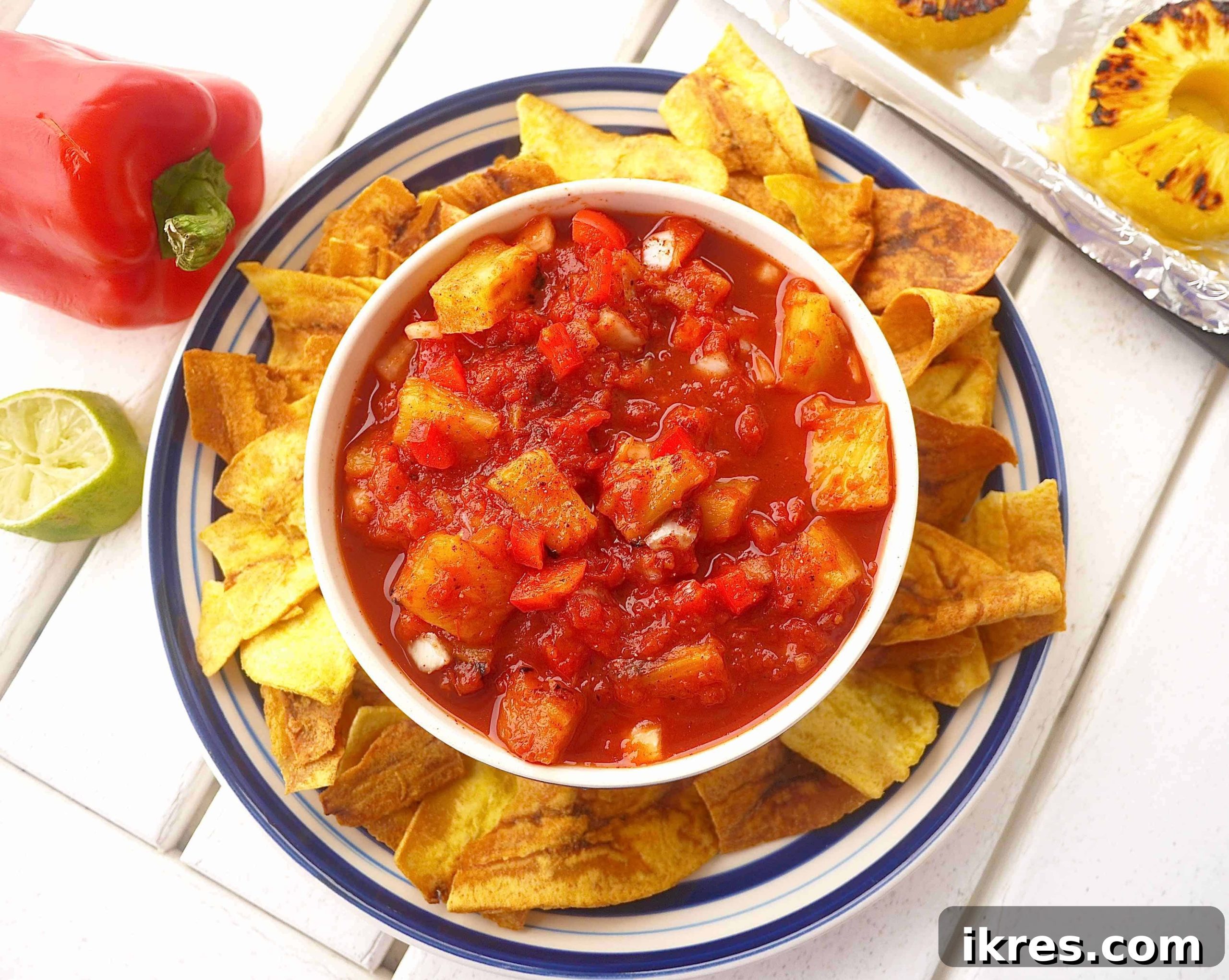 Sunshine & Smoke Salsa 7 A large, inviting bowl of fresh grilled pineapple salsa, beautifully surrounded by an abundant spread of crispy tortilla chips, perfect for a party or gathering.