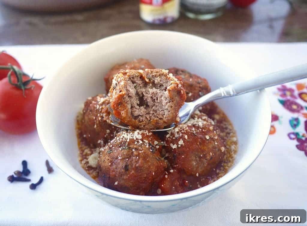 Wholesome Almond Flour Meatballs with Savory Sauce 3 Close-up of a bowl of gluten-free Italian meatballs, with one meatball cut open to show its tender interior.