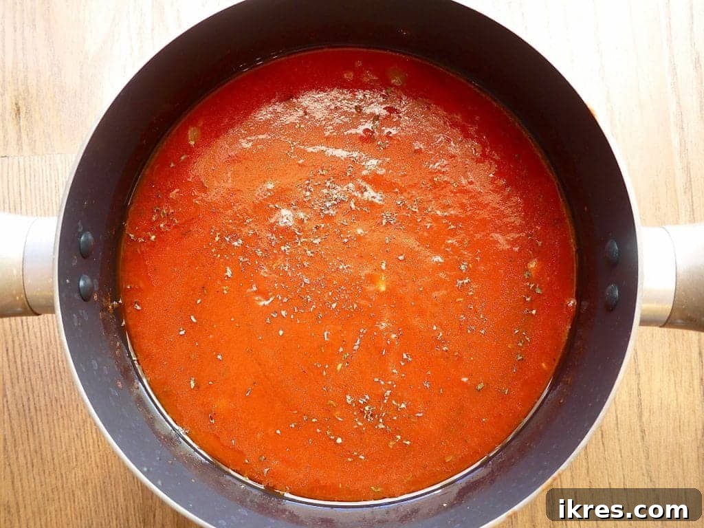 Wholesome Almond Flour Meatballs with Savory Sauce 6 Marinara sauce ingredients, including strained and crushed tomatoes, spices, and honey, in a pot before simmering.