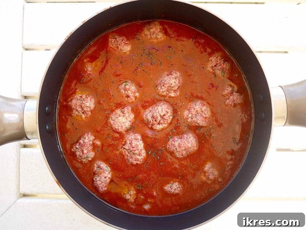 Wholesome Almond Flour Meatballs with Savory Sauce 7 Uncooked gluten-free meatballs gently placed into a pot of marinara sauce.