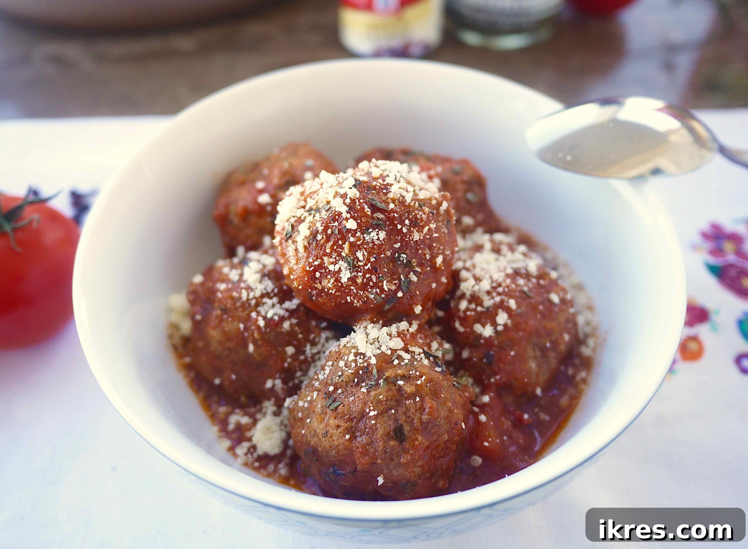 Wholesome Almond Flour Meatballs with Savory Sauce 9 A bowl of almond flour meatballs and sauce, garnished with fresh Parmesan cheese and herbs.