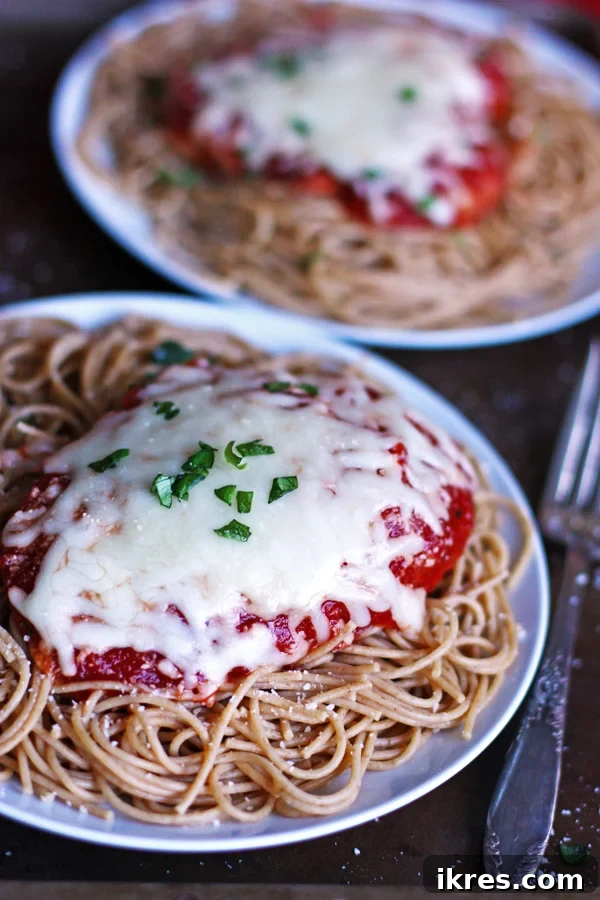 Parmesan Chicken Perfection 2 Delicious Chicken Parmesan with a unique Chili Sauce twist, served with pasta and fresh herbs.