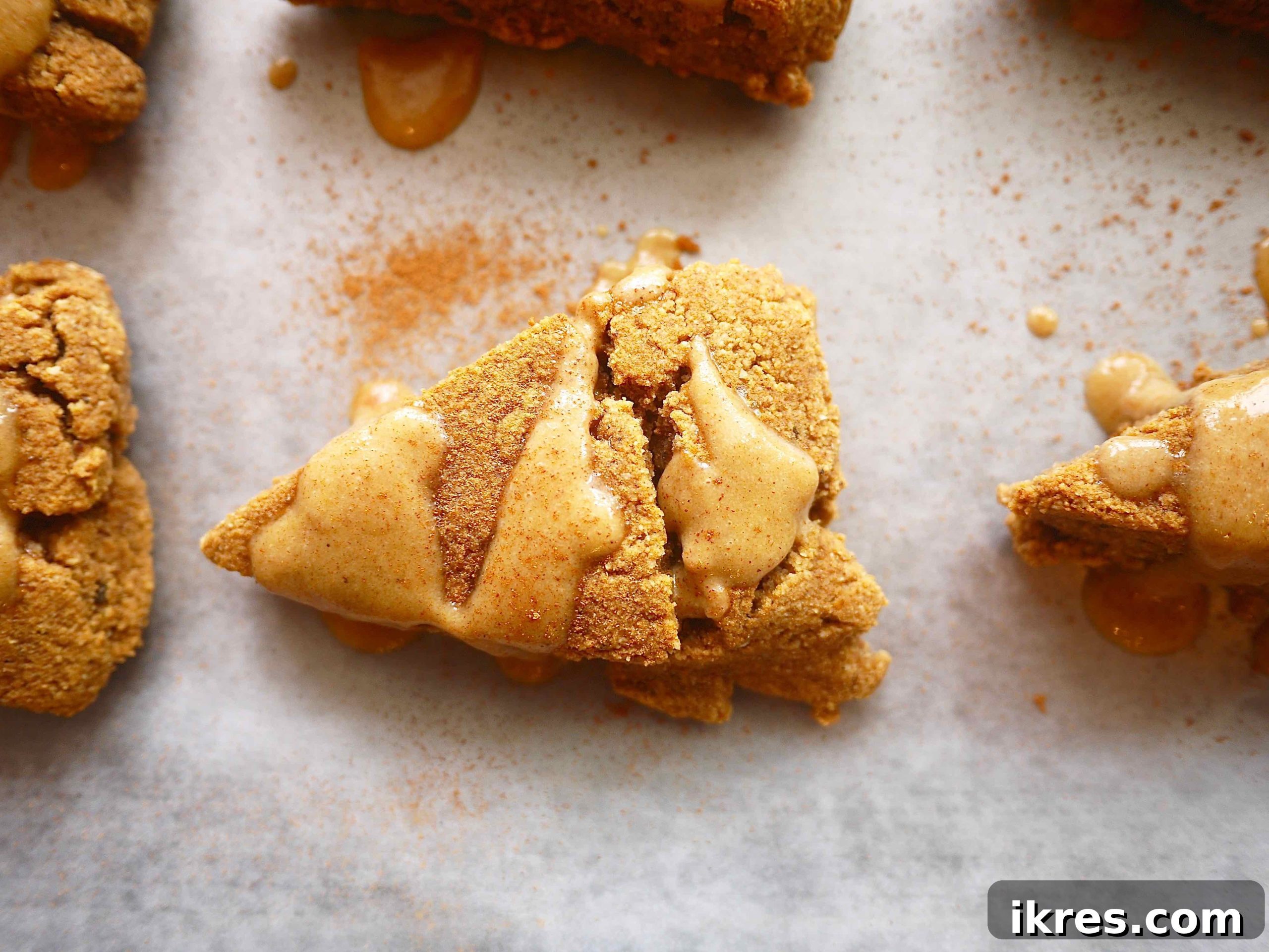 Gluten-Free Paleo Pumpkin Scones 6 Gluten-free pumpkin scones with a generous amount of frosting on top, ready for serving.