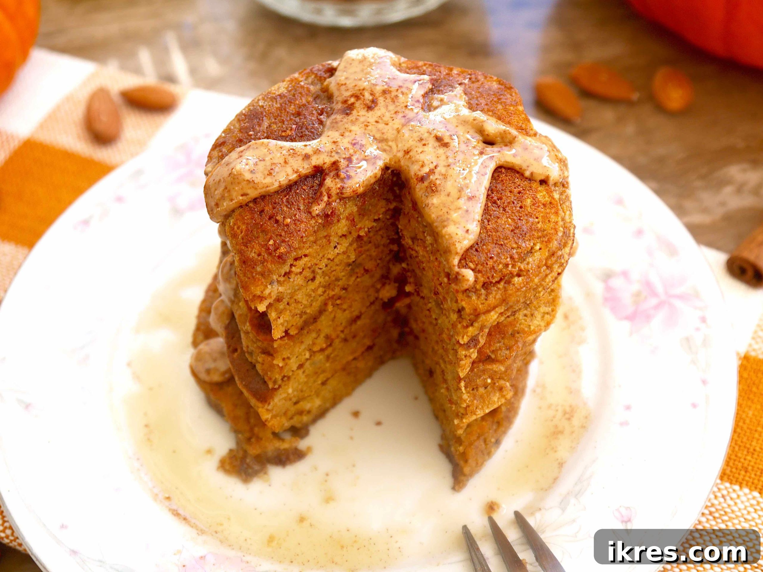 Gluten-free pumpkin pancakes topped with a generous swirl of almond butter and a drizzle of maple syrup, ready to be served.