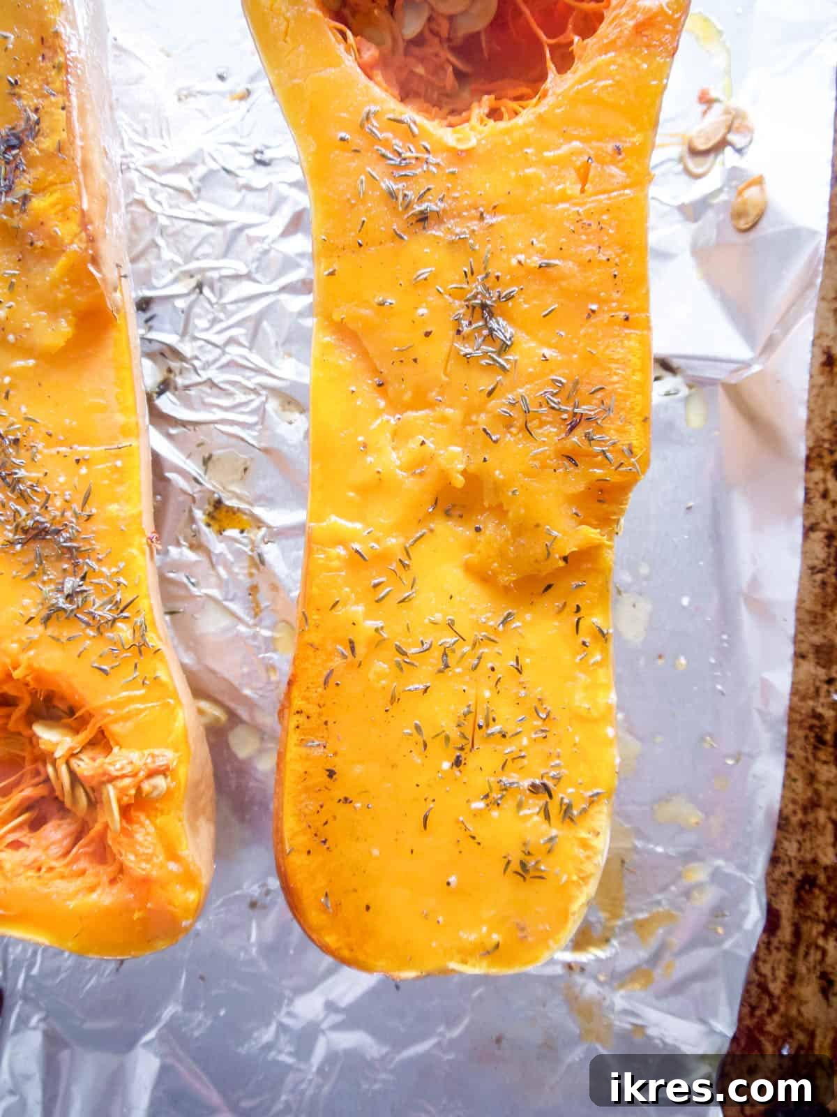 Butternut squash halves roasted on a baking sheet.