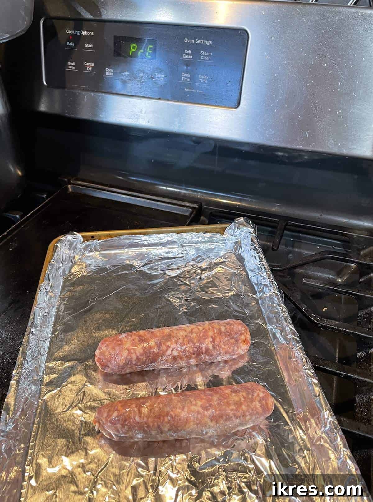 Perfect Oven-Roasted Italian Sausage 3 Two uncooked Italian sausages with an oven preheating in the background.