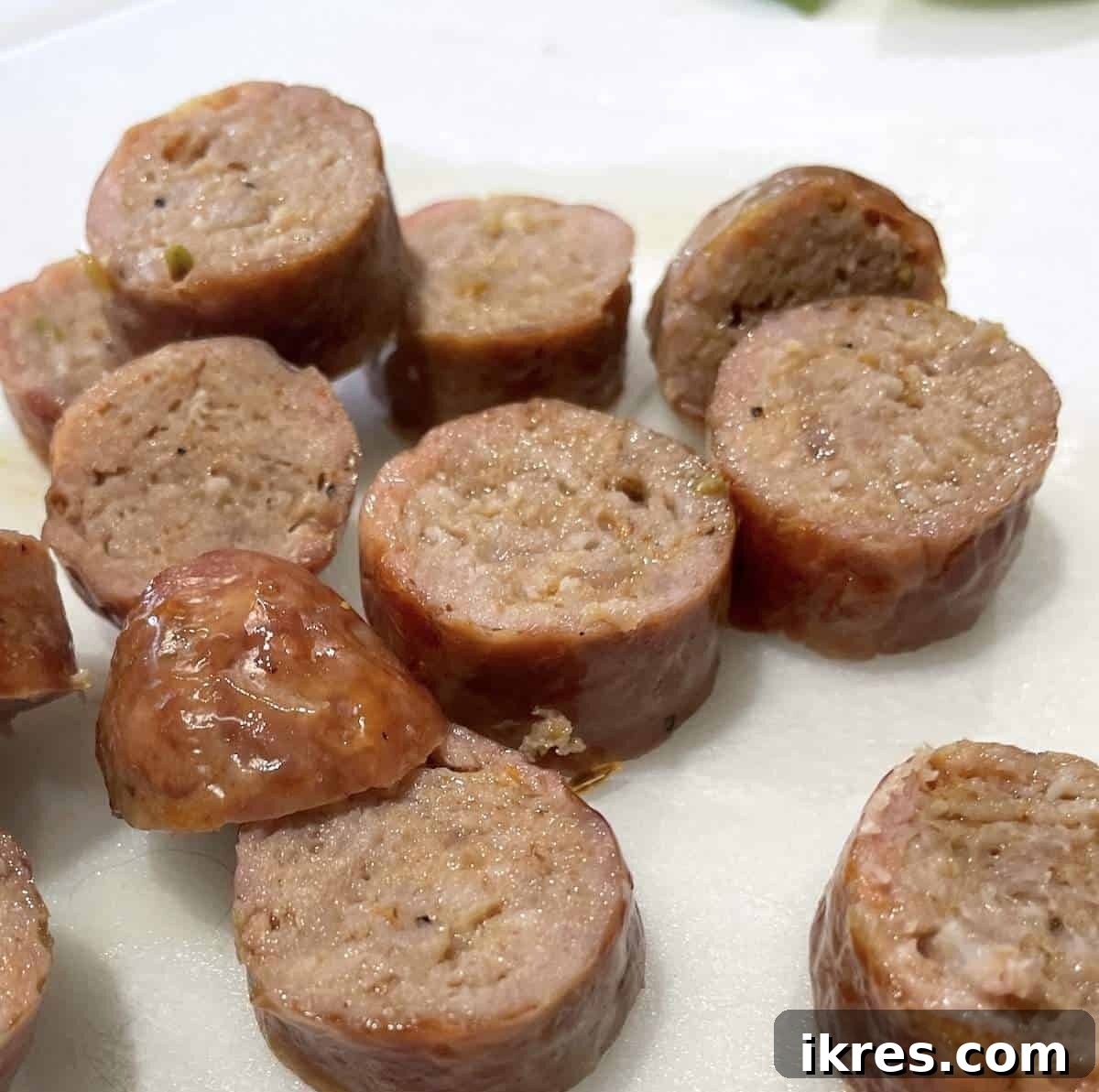 Perfect Oven-Roasted Italian Sausage 6 Oven-baked, sliced Italian sausage on a white cutting board.
