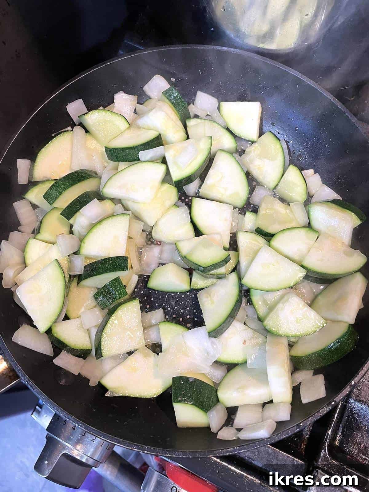 Perfect Oven-Roasted Italian Sausage 7 A frying pan with sautéed zucchini and onions cooking in it.