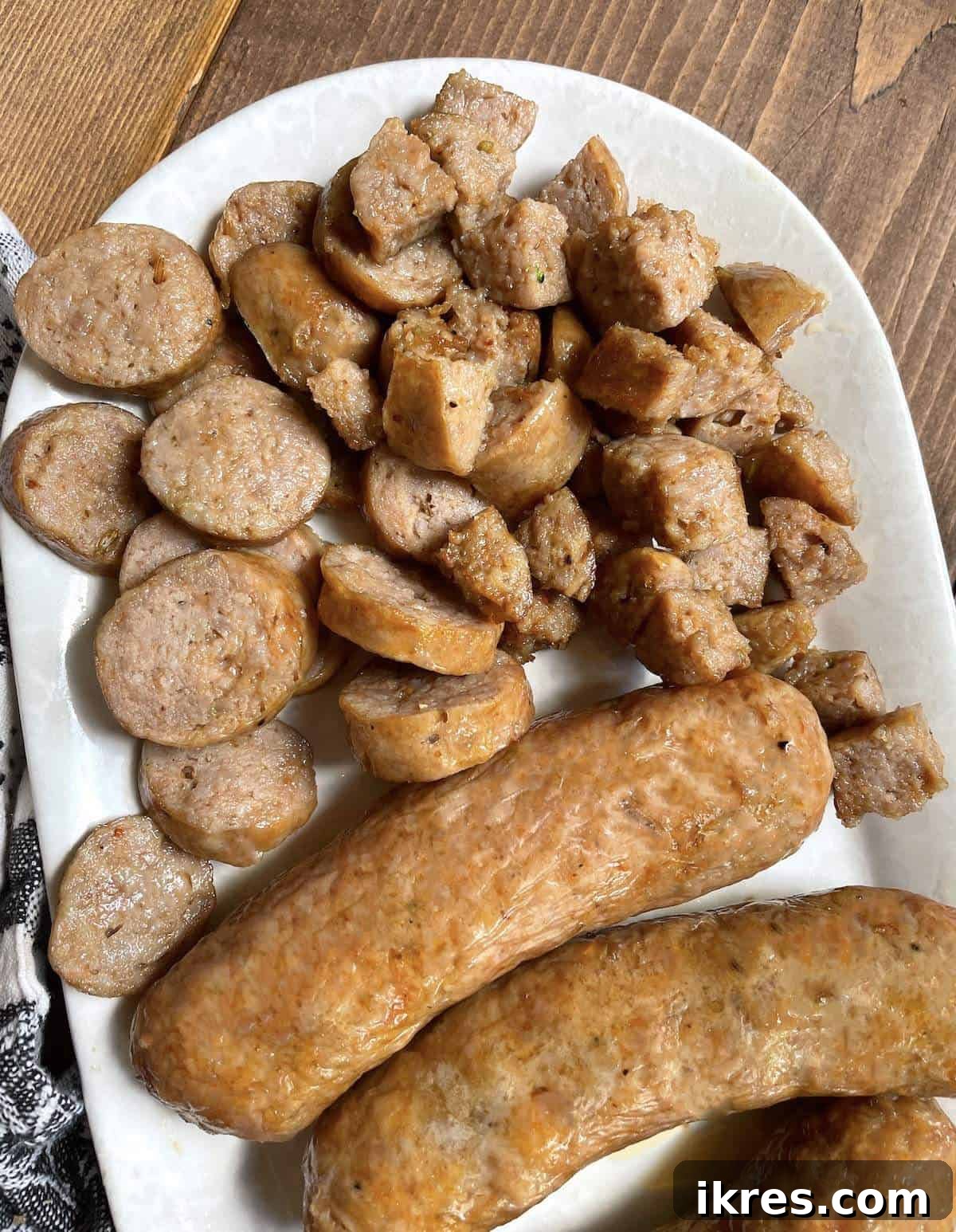 Air Fryer Italian Sausage Perfection 2 Air fried Italian sausage cut different ways on a white plate.