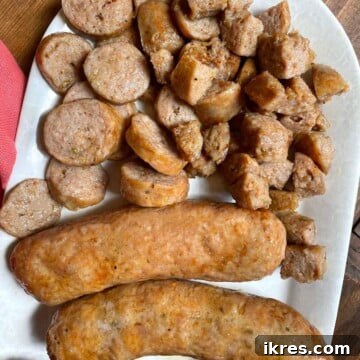 A white plate with cooked air fryer Italian sausage on it. Some whole and some cut.