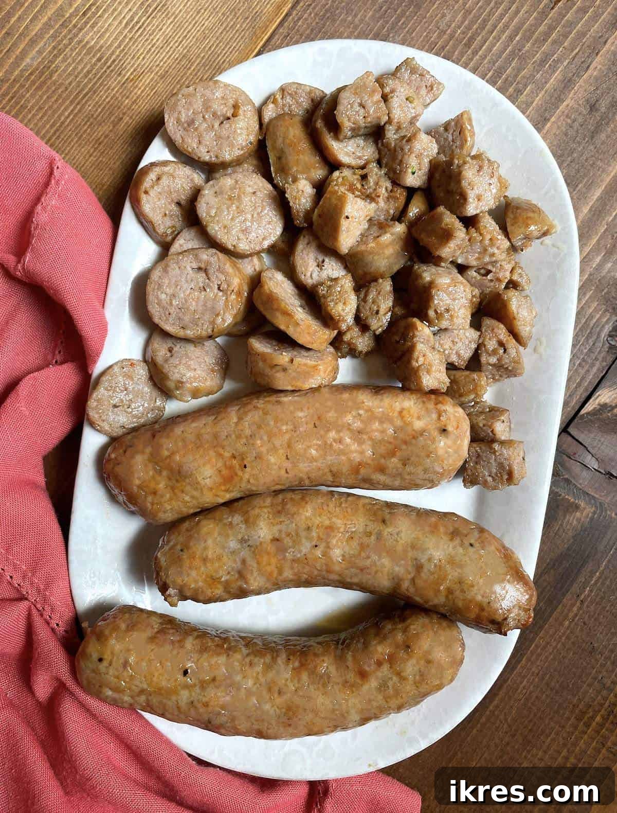 Air Fryer Italian Sausage Perfection 6 Air fried Italian sausages cut in different ways on a white plate with a pink napkin.