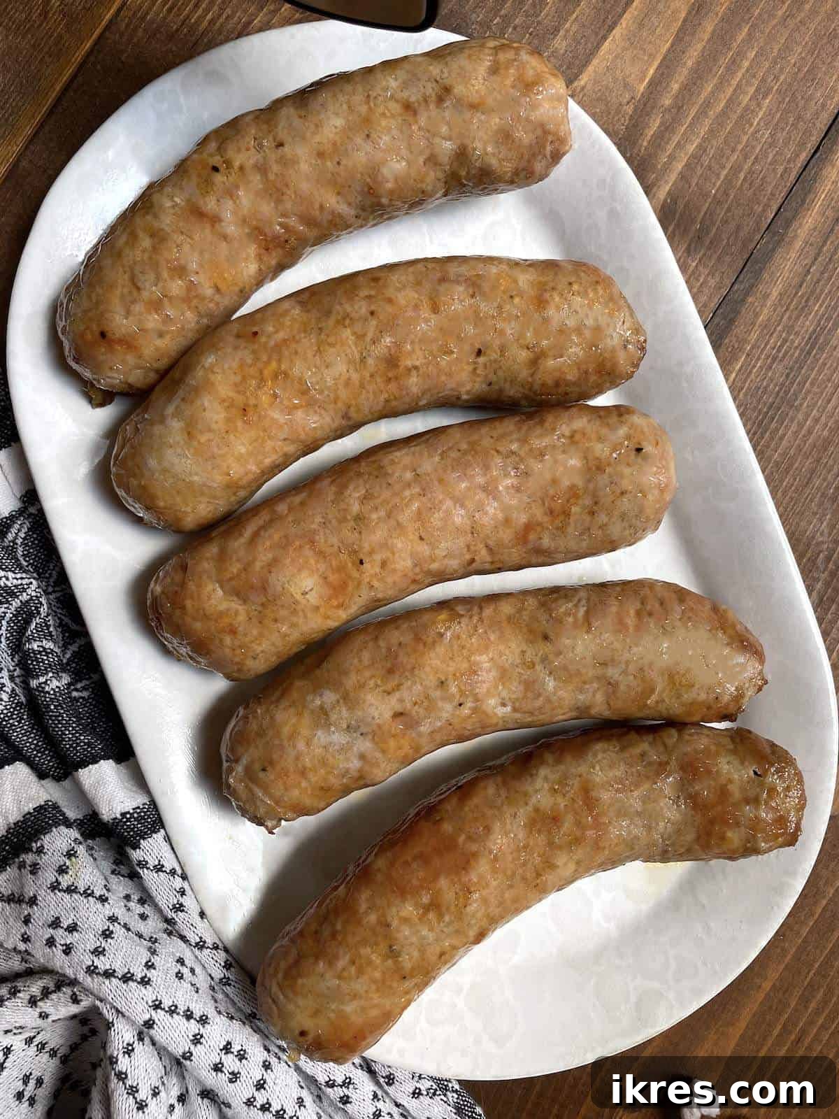 Air Fryer Italian Sausage Perfection 10 Whole cooked air fried Italian sausages on a white plate.