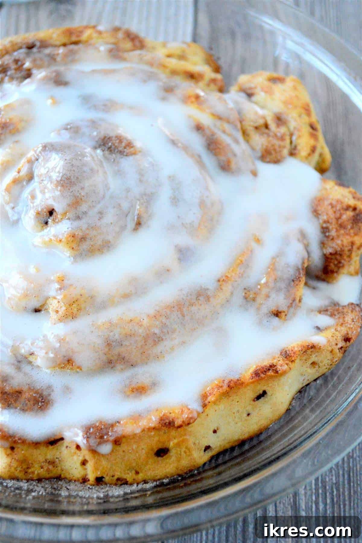 A fully glazed giant fluffy cinnamon roll, ready to be sliced and served.