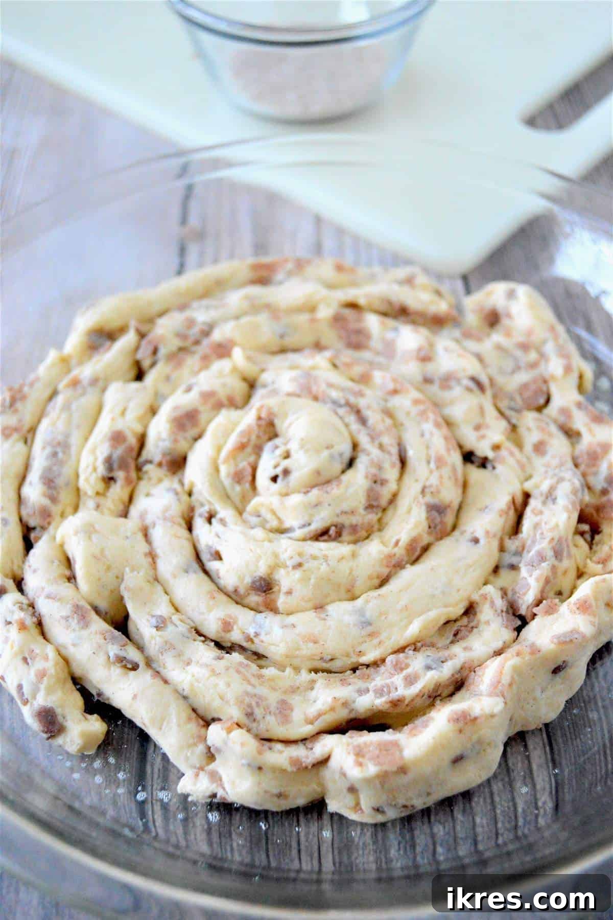 Unbaked giant cinnamon roll dough completely rolled out to fill a round baking dish.