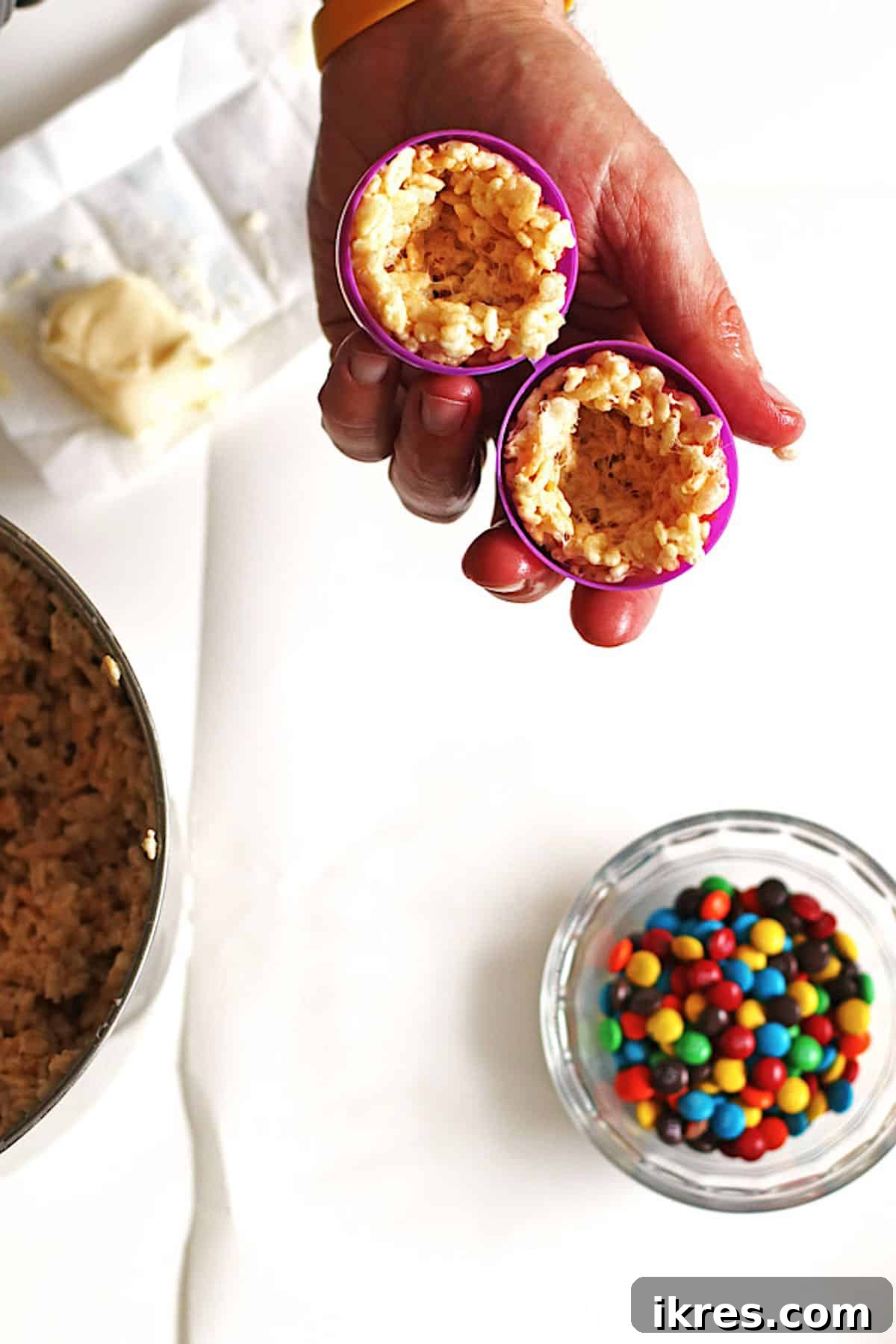 Egg-Cellent Crispy Easter Bites 4 Rice Krispie treat mixture pressed into each half of a plastic Easter egg, creating a hollow center ready for candy.