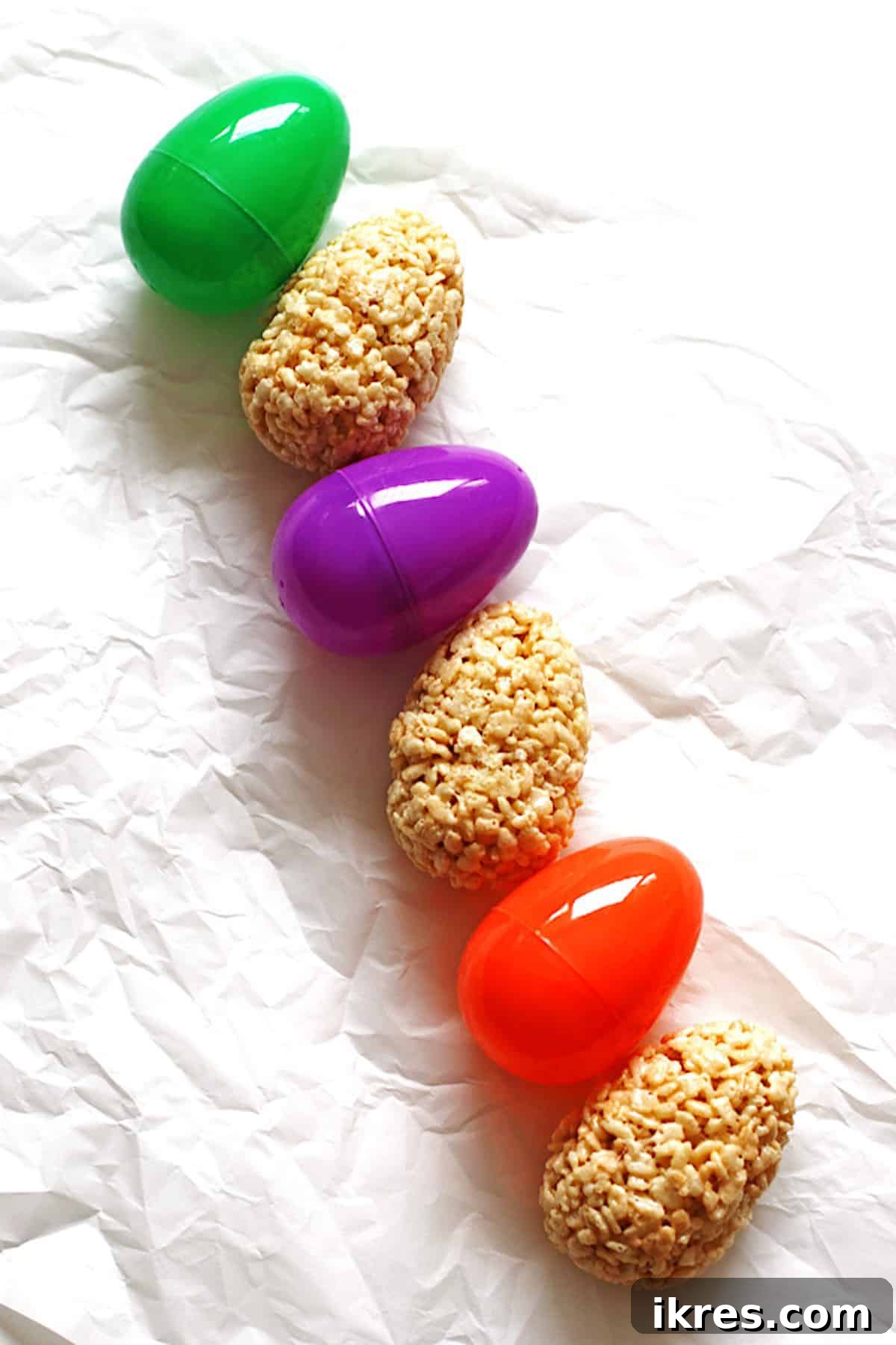 Egg-Cellent Crispy Easter Bites 6 A charming display of finished Rice Krispie Treat Easter eggs lined up alongside colorful plastic Easter eggs, ready for celebration.