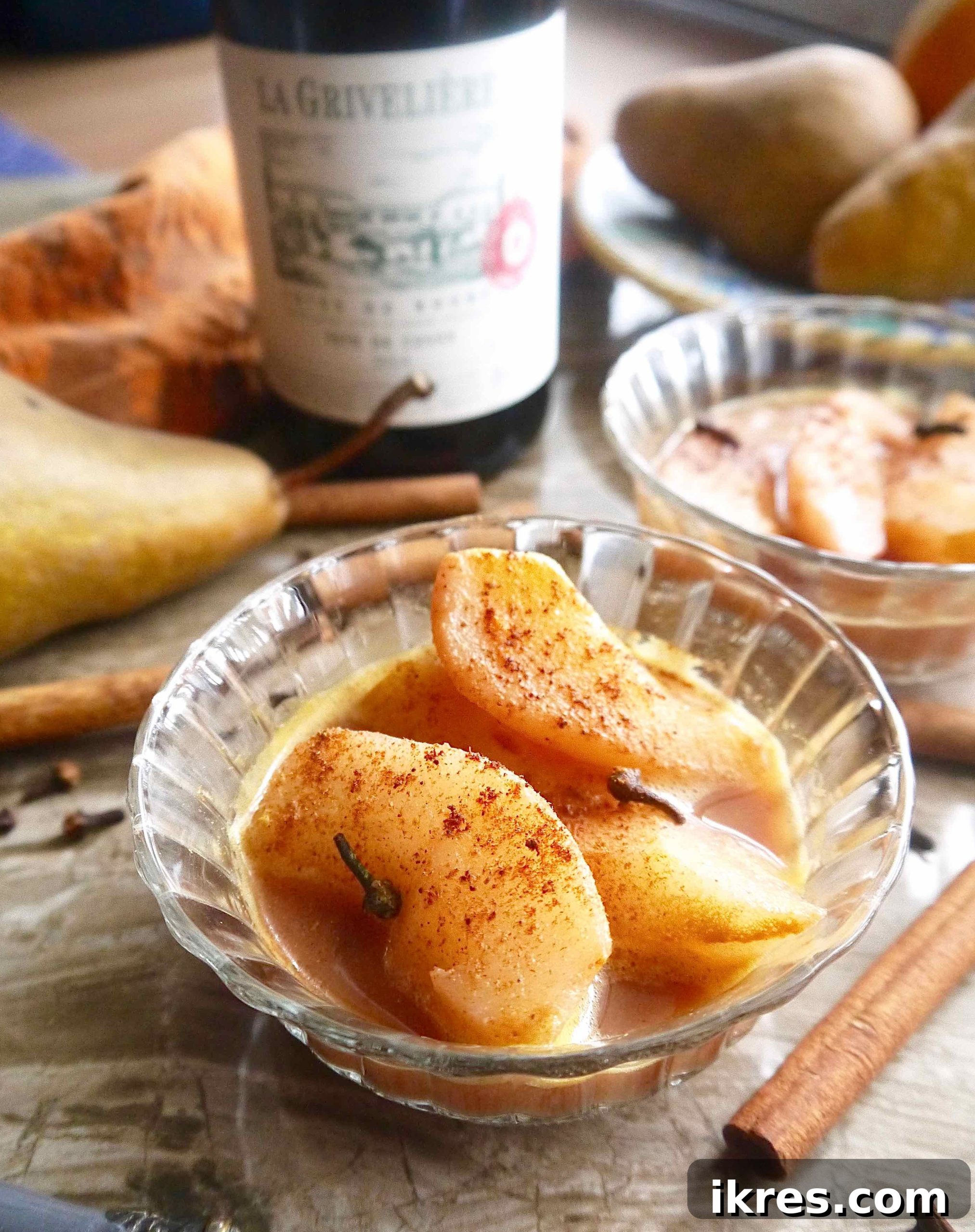 Crimson Pears with Zesty Spice Infusion 2 Spiced Poached Pears in a beautiful bowl, bathed in a shimmering red wine and orange juice sauce, ready to be served.