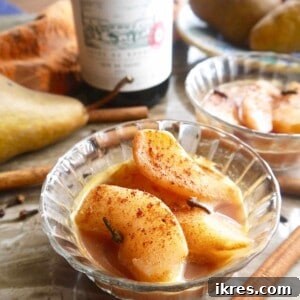 Spiced Poached Pears in a bowl with a red wine and orange juice sauce.