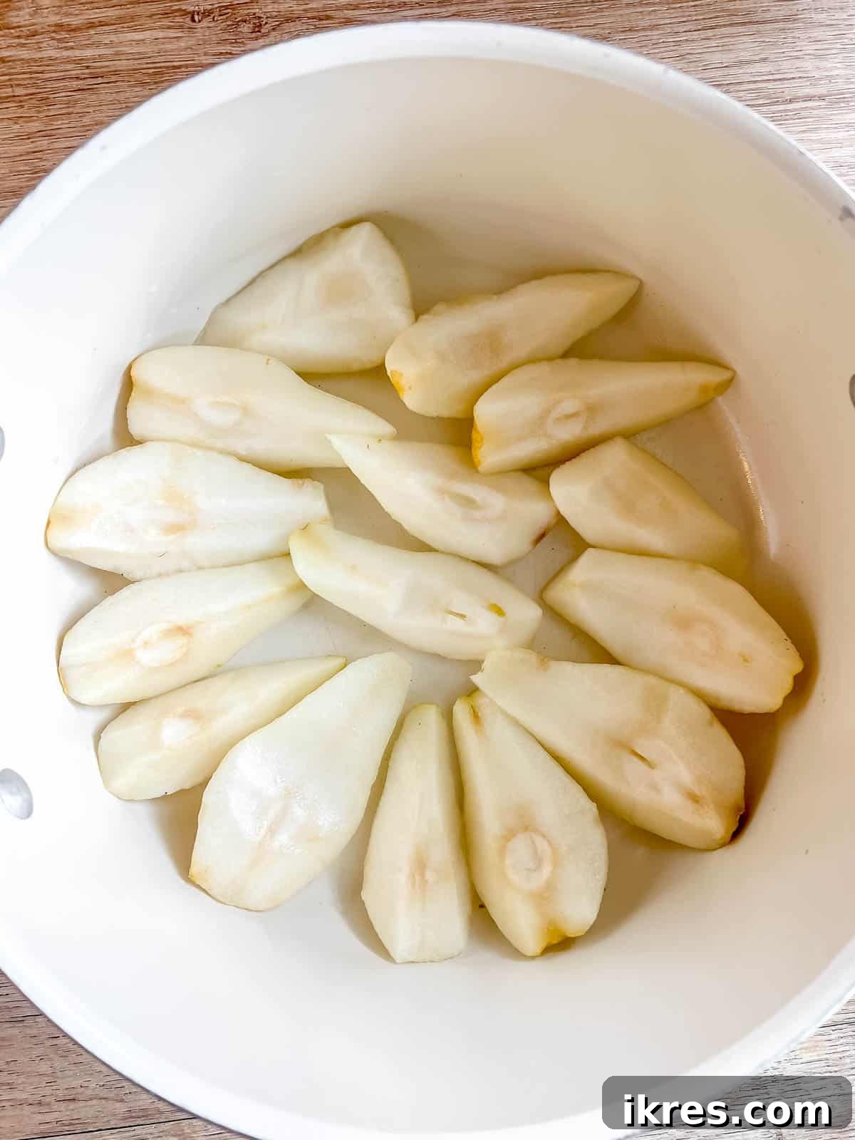 Crimson Pears with Zesty Spice Infusion 5 Peeled and quartered pears neatly arranged in a large soup pan, ready for poaching.