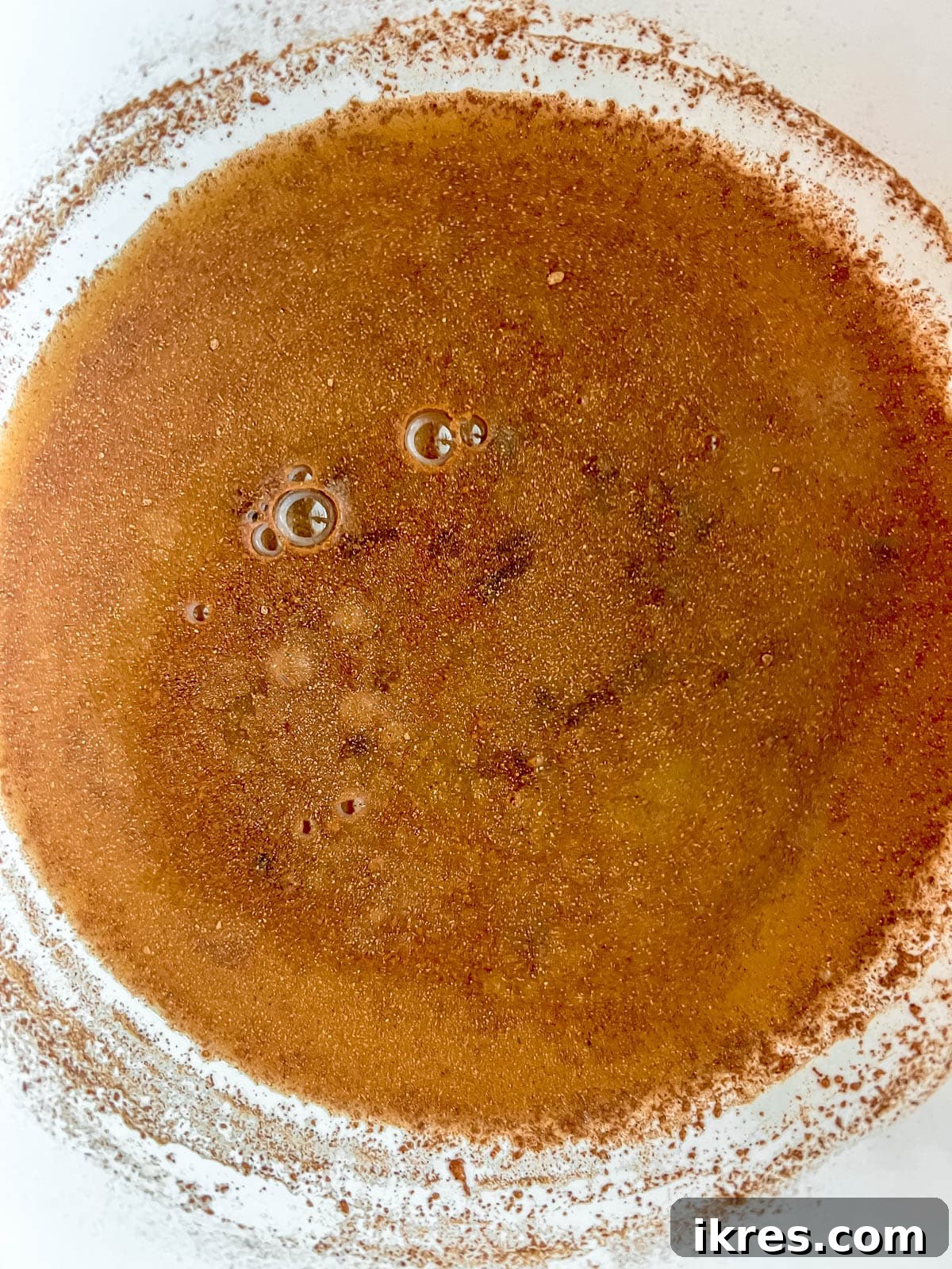 Crimson Pears with Zesty Spice Infusion 6 Orange juice being mixed with ground spices including nutmeg, cinnamon, and cloves in a small bowl.