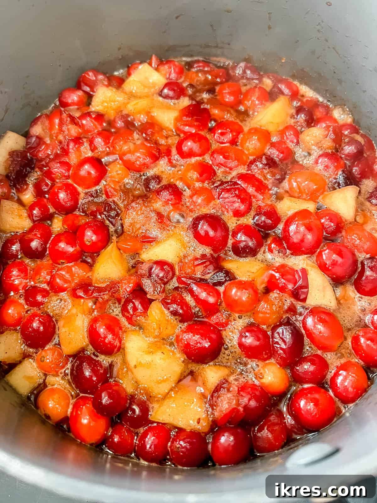 Ruby Apple Cranberry Compote 6 Homemade cranberry apple sauce simmering gently in a saucepan, with cranberries bursting and apples softening.