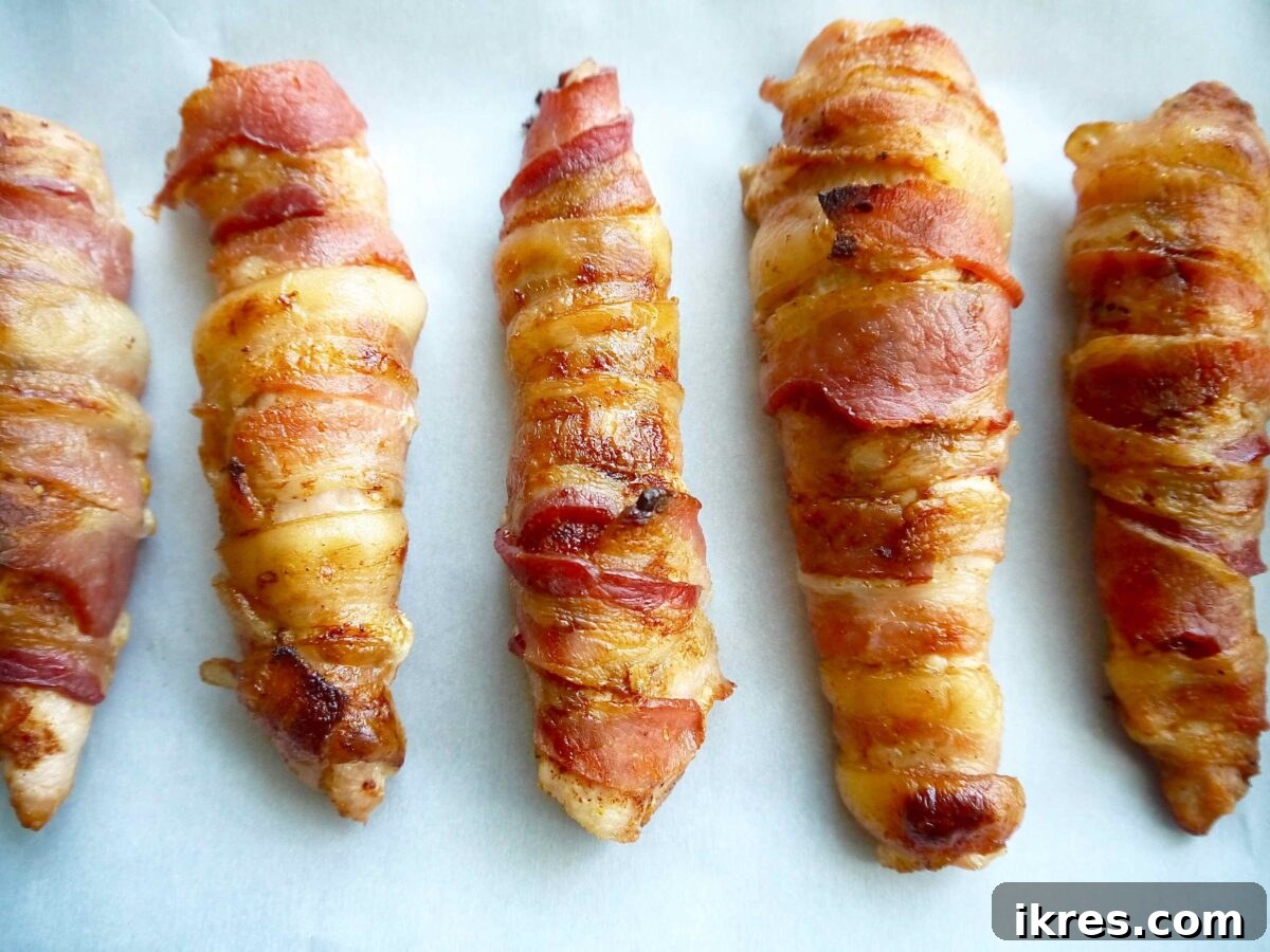 Guilt Free Paleo Keto Bacon Wrapped Chicken Tenders 7 Freshly baked bacon wrapped chicken tenders, golden and crispy, removed from the oven.